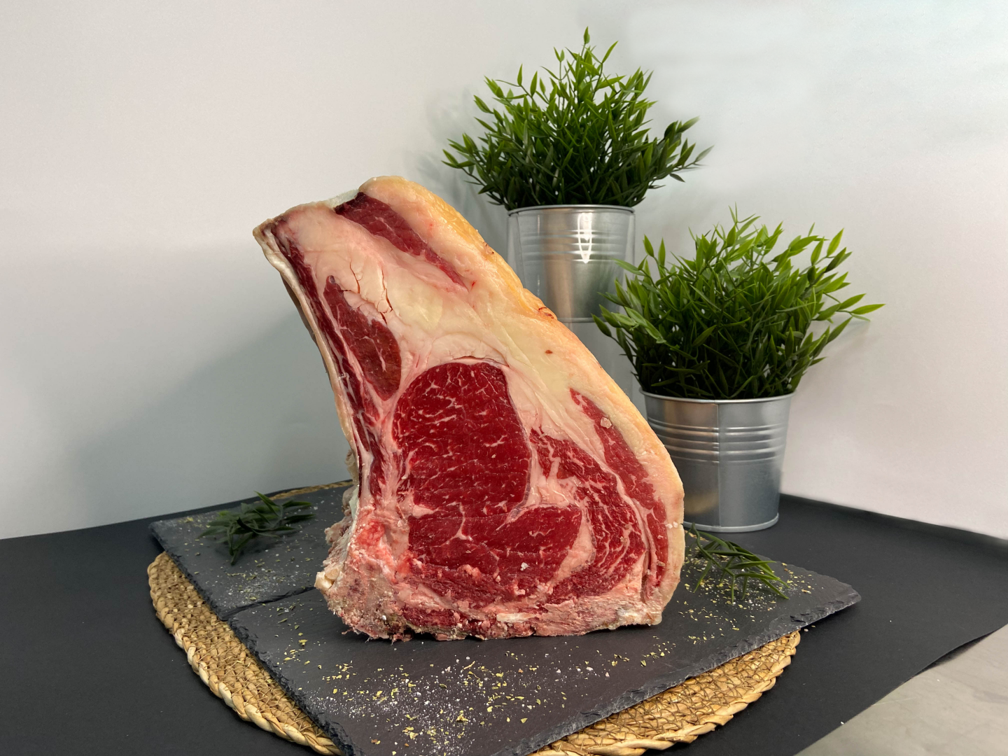 Chuletón sobre una tabla de pizarra, acompañado de romero
